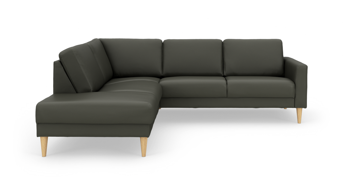 Mørkegrøn L‑sofa med chaiselong til venstre og koniske ben i lyst træ på hvid baggrund.