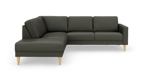 Mørkegrøn L‑sofa med chaiselong til venstre og koniske ben i lyst træ på hvid baggrund.