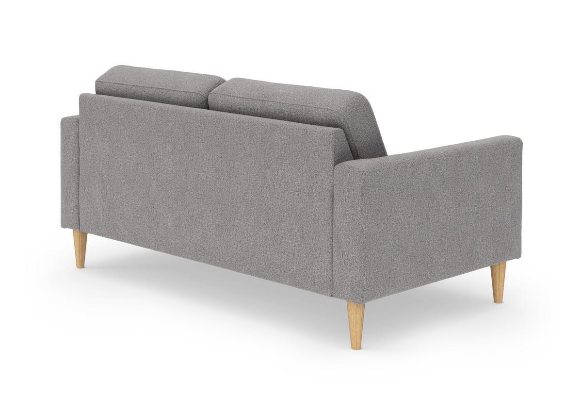 Grå sofa med lyse træben set skråt bagfra på hvid baggrund.