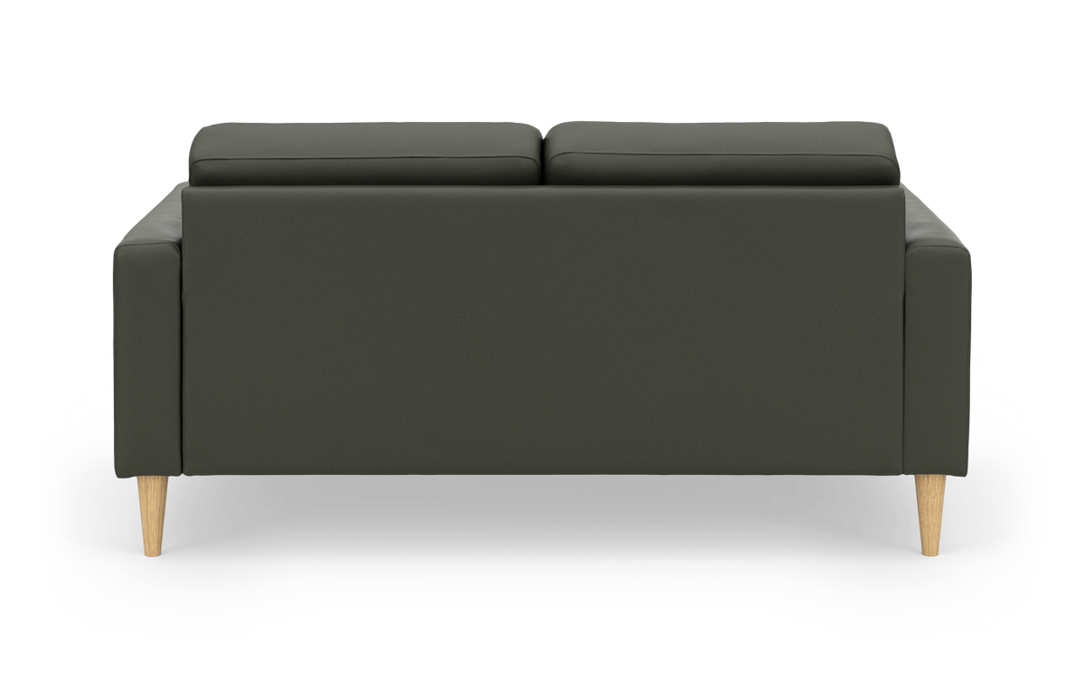 Mørkegrøn sofa med to ryghynder set bagfra, lyse træben, frilagt på hvid baggrund.