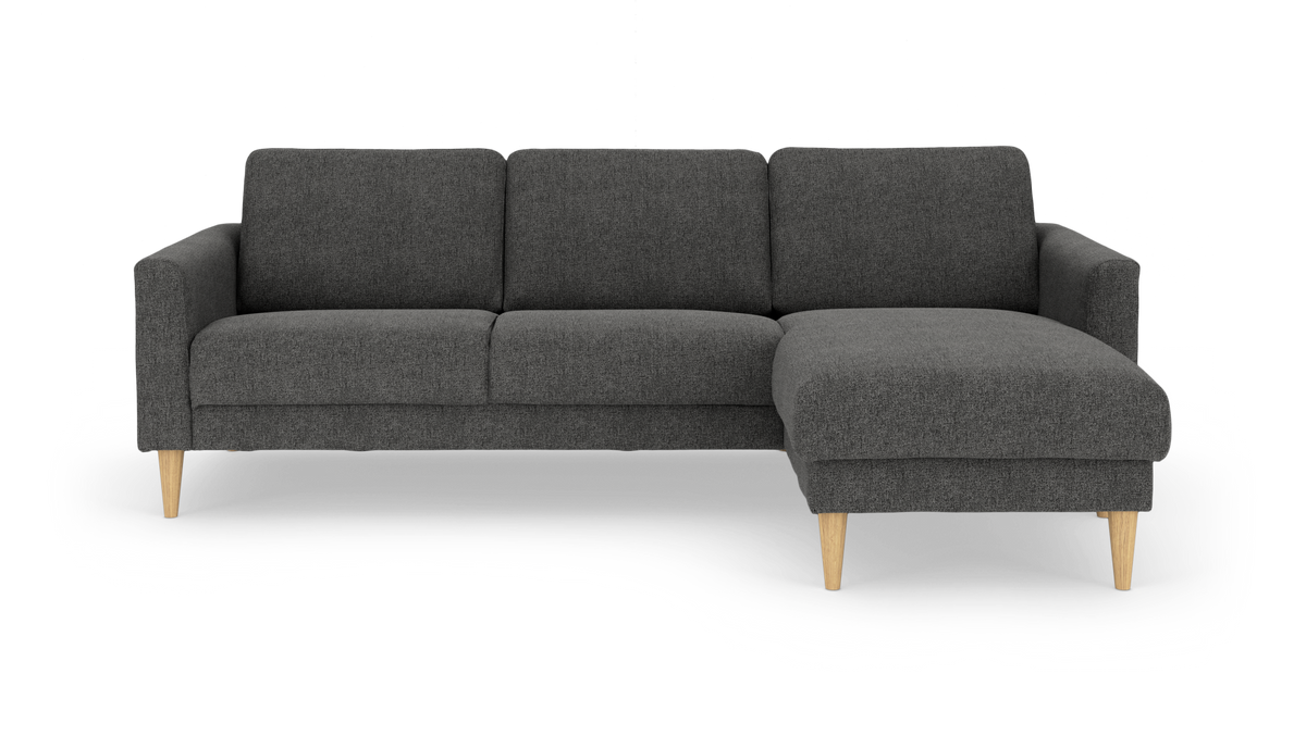 Mørkegrå hjørnesofa med chaiselong på højre side og lyse egetræsben, frilagt på hvid baggrund.