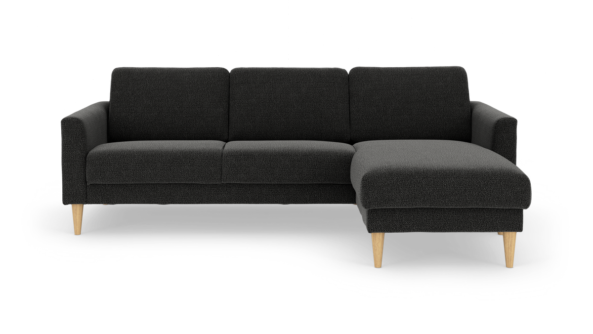 Mørkegrå sofa med chaiselong til højre og lyse, koniske træben – frilagt produktbillede.