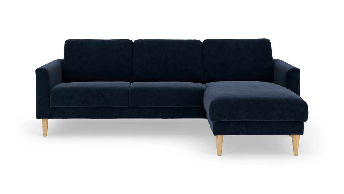 Mørkeblå hjørnesofa med chaiselong til højre og lyse træben, frilagt på hvid baggrund.