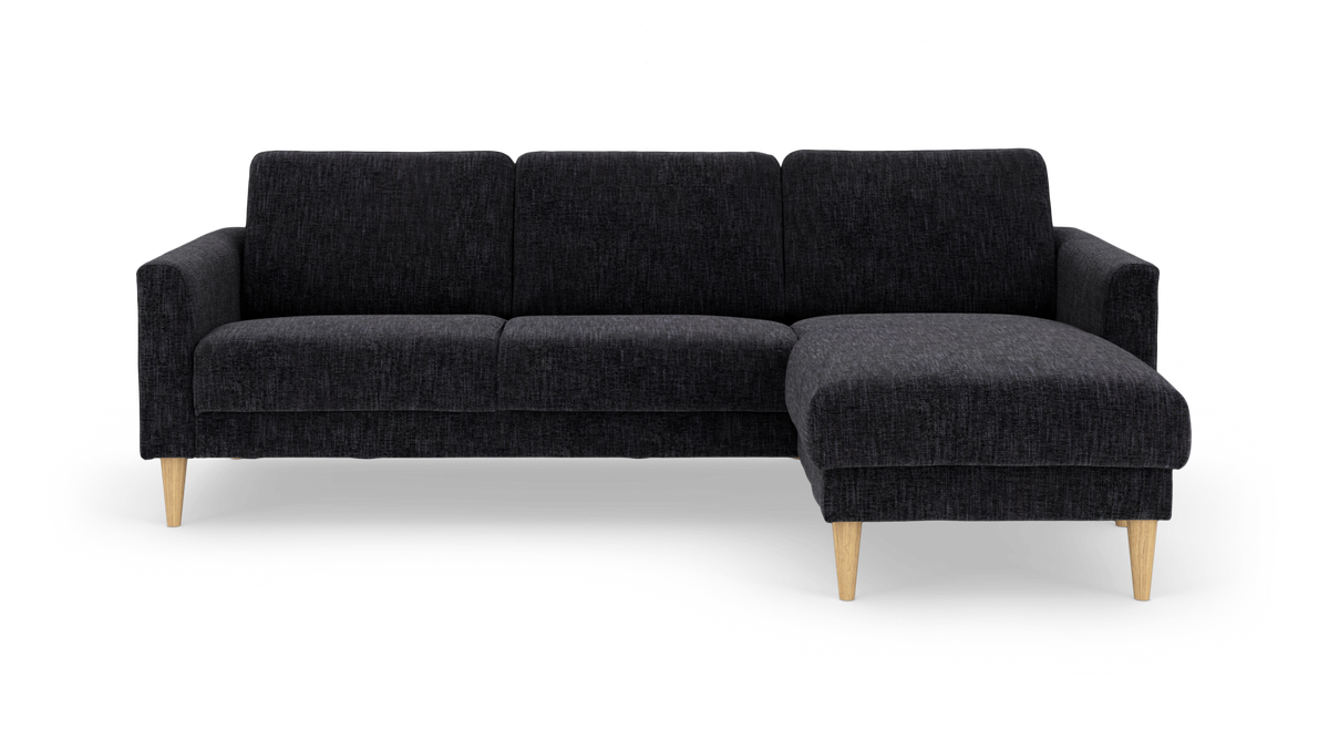 Mørkegrå hjørnesofa med chaiselong til højre og lyse træben.