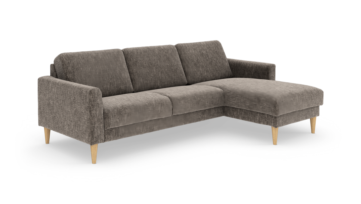 Grå stofsofa med højrevendt chaiselong og tilspidsede træben, frilagt på hvid baggrund.