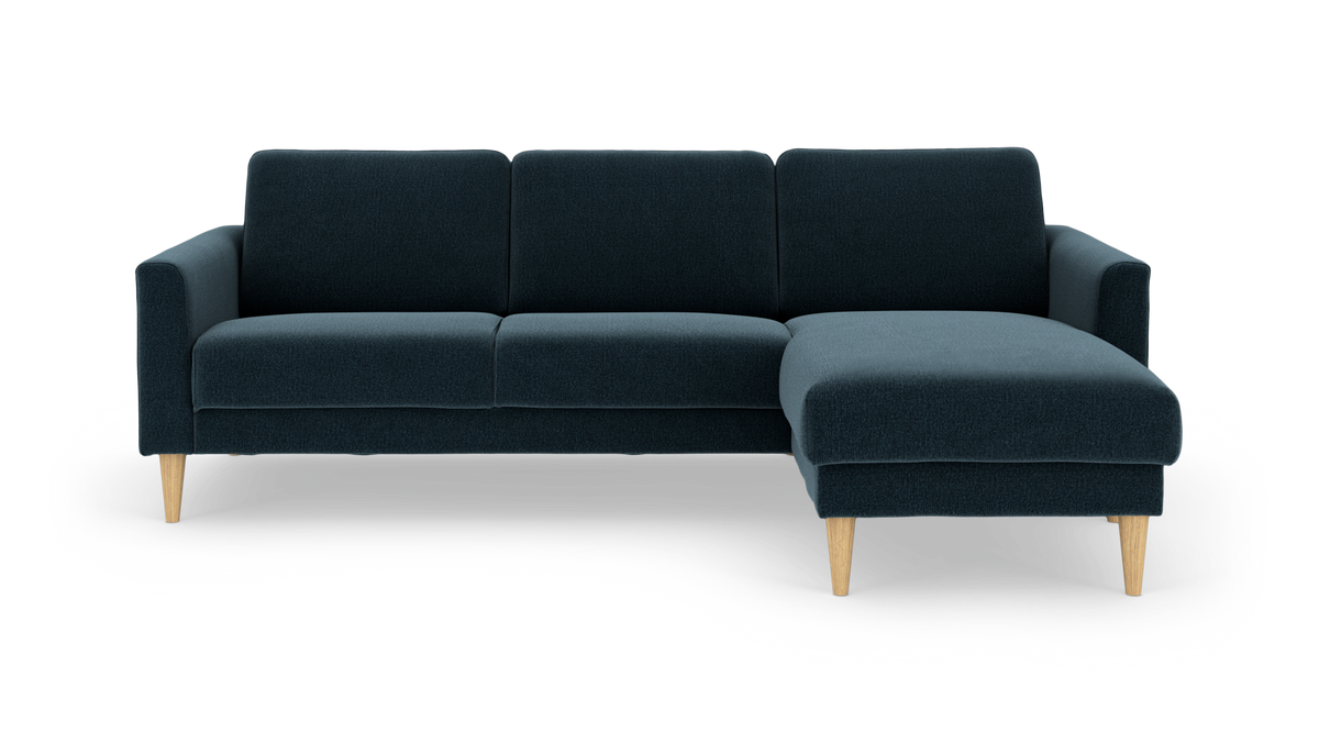 Mørkeblå hjørnesofa med chaiselong til højre og koniske ben i lyst træ, fritlagt på hvid baggrund.