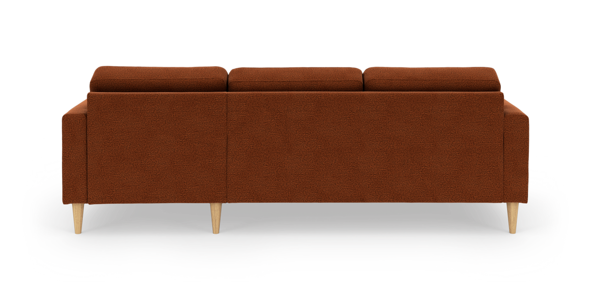 Bagside af tredelt sofa i rustfarvet bouclé med koniske ben i lyst træ.