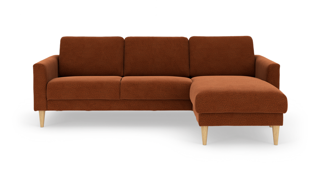 Rustrød hjørnesofa med chaiselong til højre og lyse træben, frilagt på hvid baggrund.