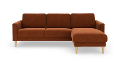 Rustrød hjørnesofa med chaiselong til højre og lyse træben, frilagt på hvid baggrund.