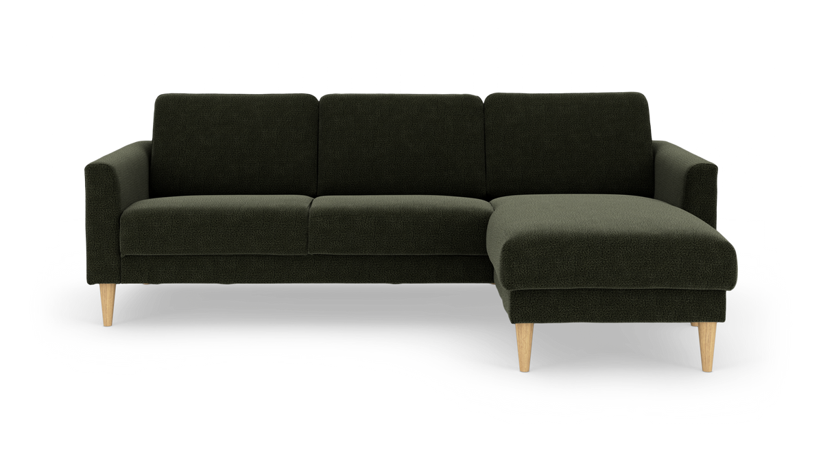 Mørkegrøn hjørnesofa med chaiselong til højre og lyse træben.