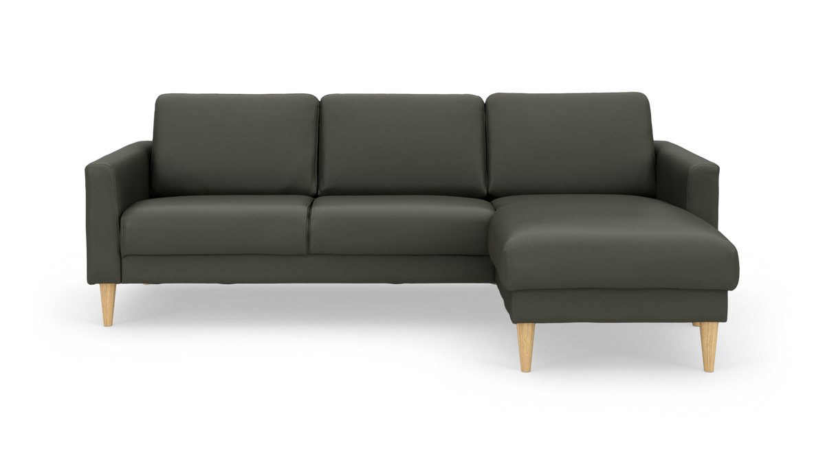 Mørkegrøn hjørnesofa med højre chaiselong og koniske ben i lyst træ, fritlagt på hvid baggrund.