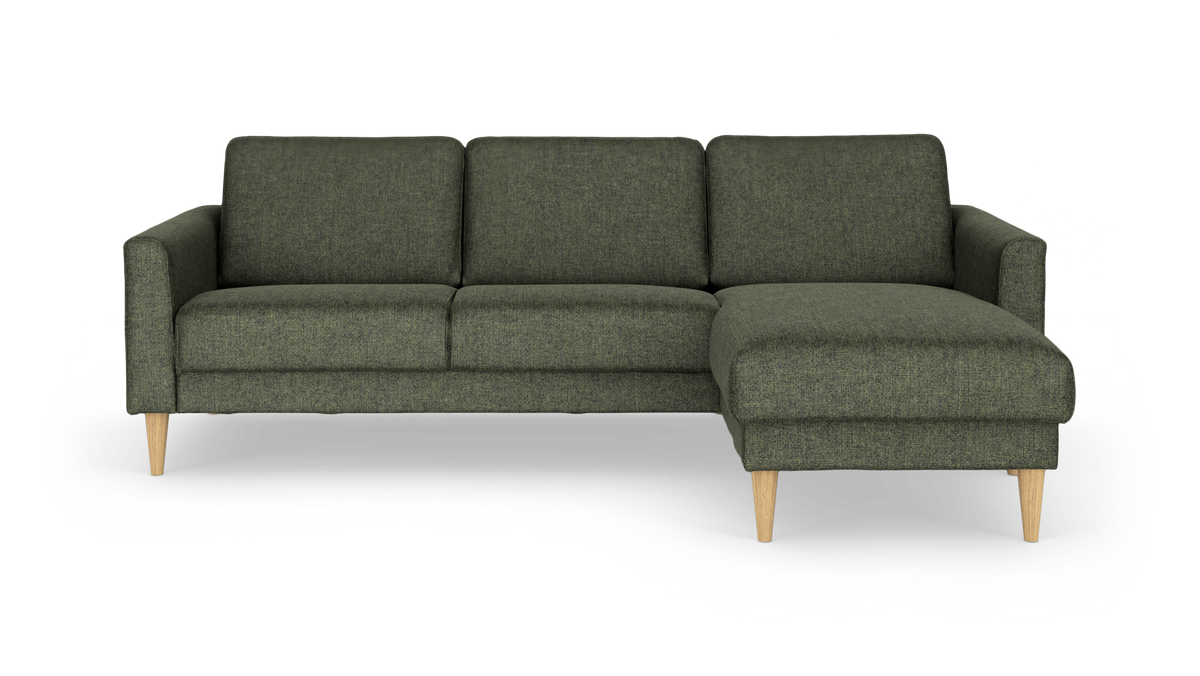 Grøn hjørnesofa med chaiselong til højre, stofbetræk og koniske ben i lyst træ, frilagt på hvid baggrund.