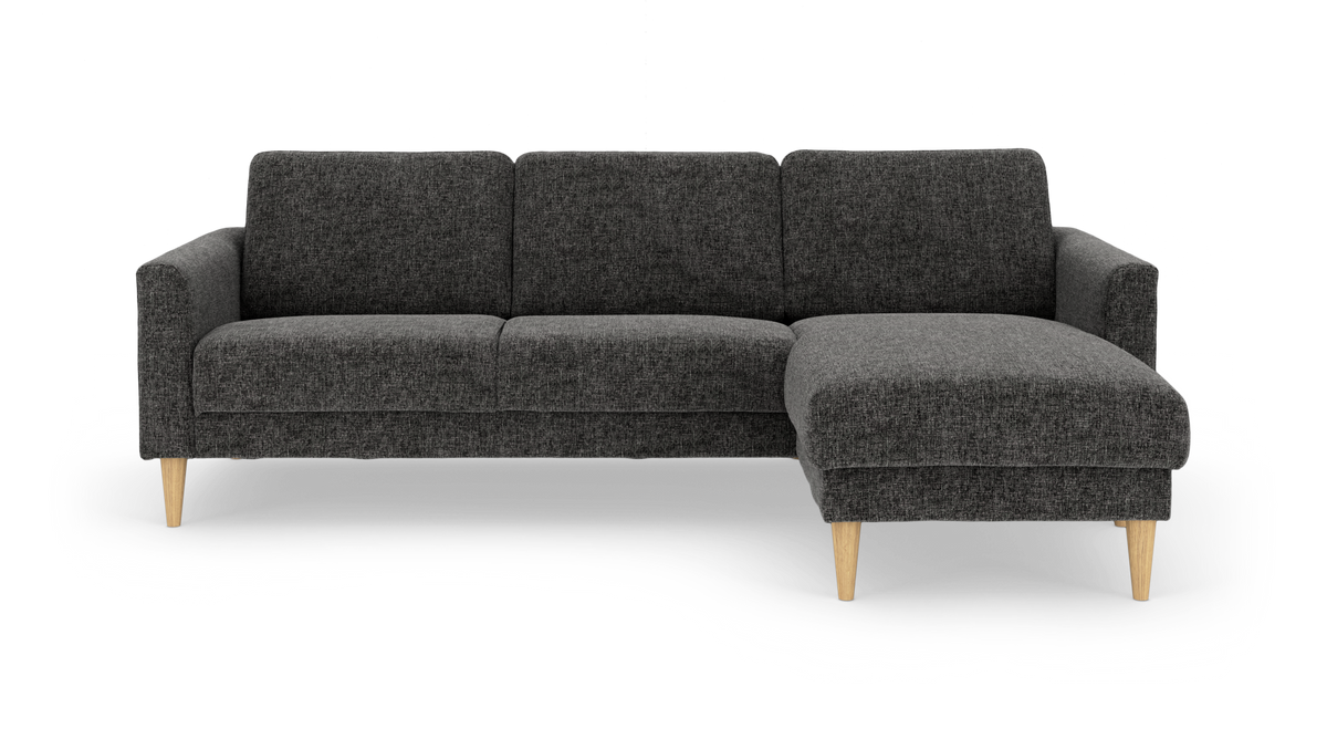 Mørkegrå hjørnesofa med chaiselong til højre og lyse træben, fritlagt på hvid baggrund.