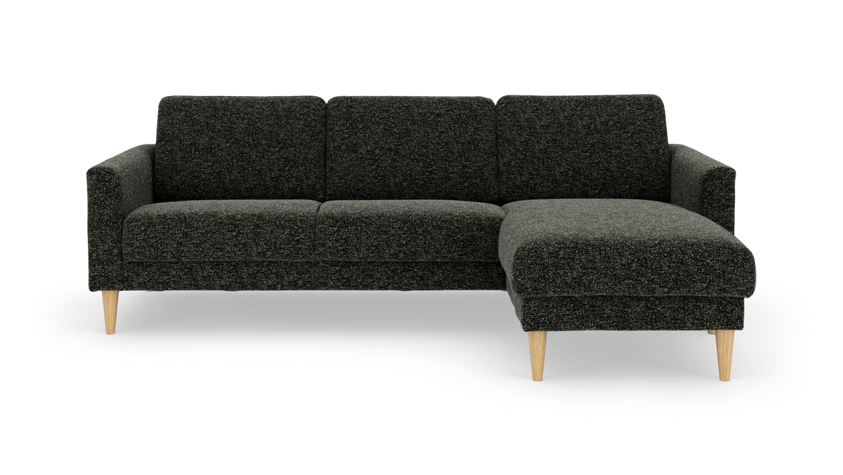 Mørkegrå hjørnesofa med chaiselong til højre og lyse træben, frilagt på hvid baggrund.
