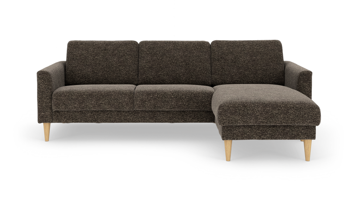 Mørkebrun hjørnesofa med chaiselong til højre og lyse træben, frilagt på hvid baggrund.