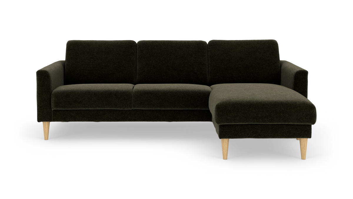 Mørkegrøn sofa med chaiselong til højre og lyse træben.