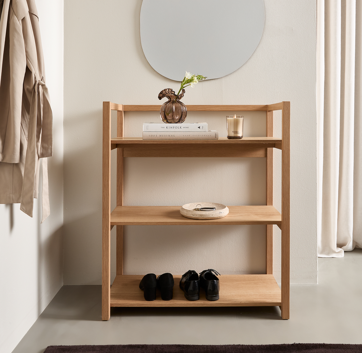 Lys entré med åben egetræshylde foran et spejl; øverste hylde har en vase med blomst, et duftlys og bøger inklusive The Kinfolk Home, midterste hylde har et fad, og nederste hylde har sorte sko.