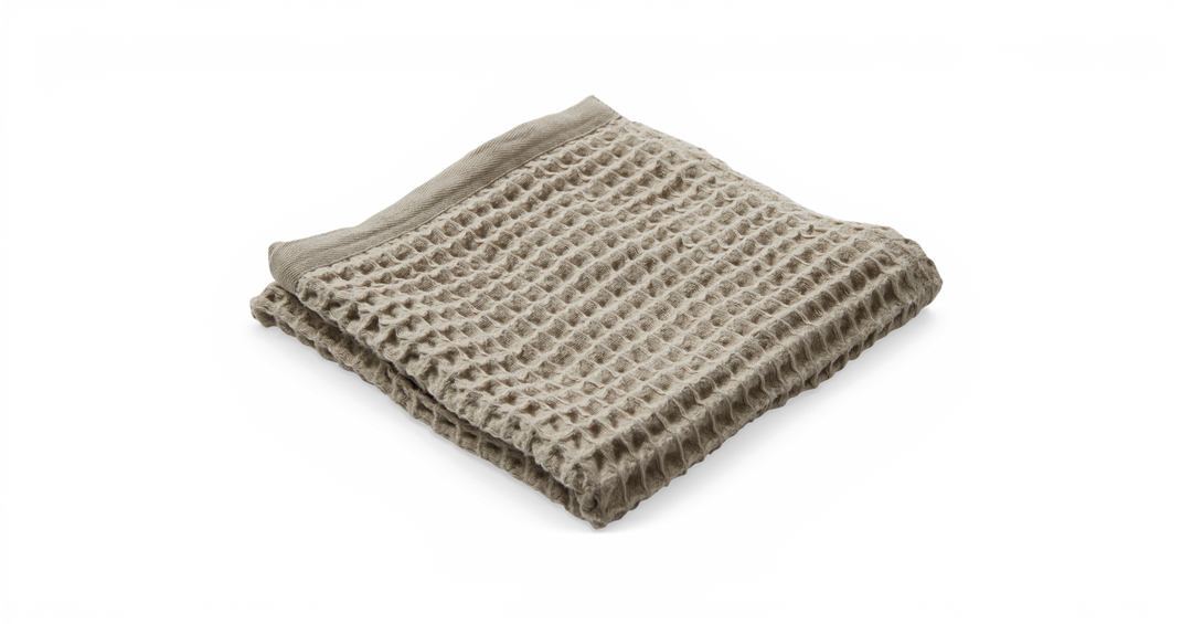 Sammenfoldet beige plaid i vaffelvævet struktur på sort baggrund.