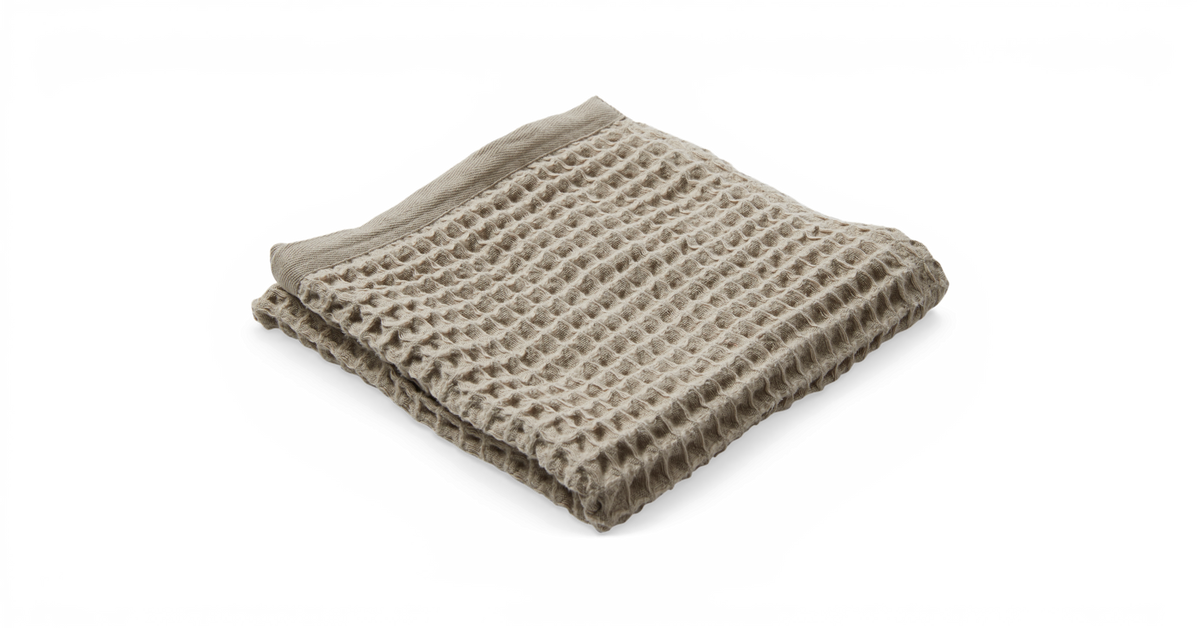 Sammenfoldet beige plaid i vaffelvævet struktur på sort baggrund.