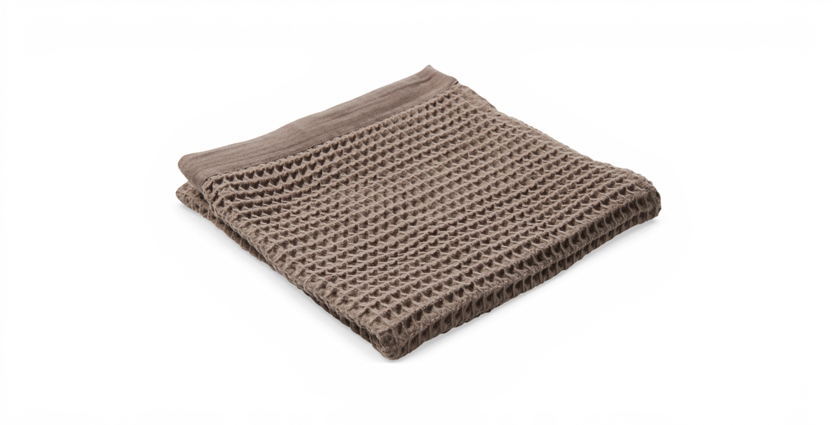 Sammenfoldet beige vaffelvævet plaid på sort baggrund.