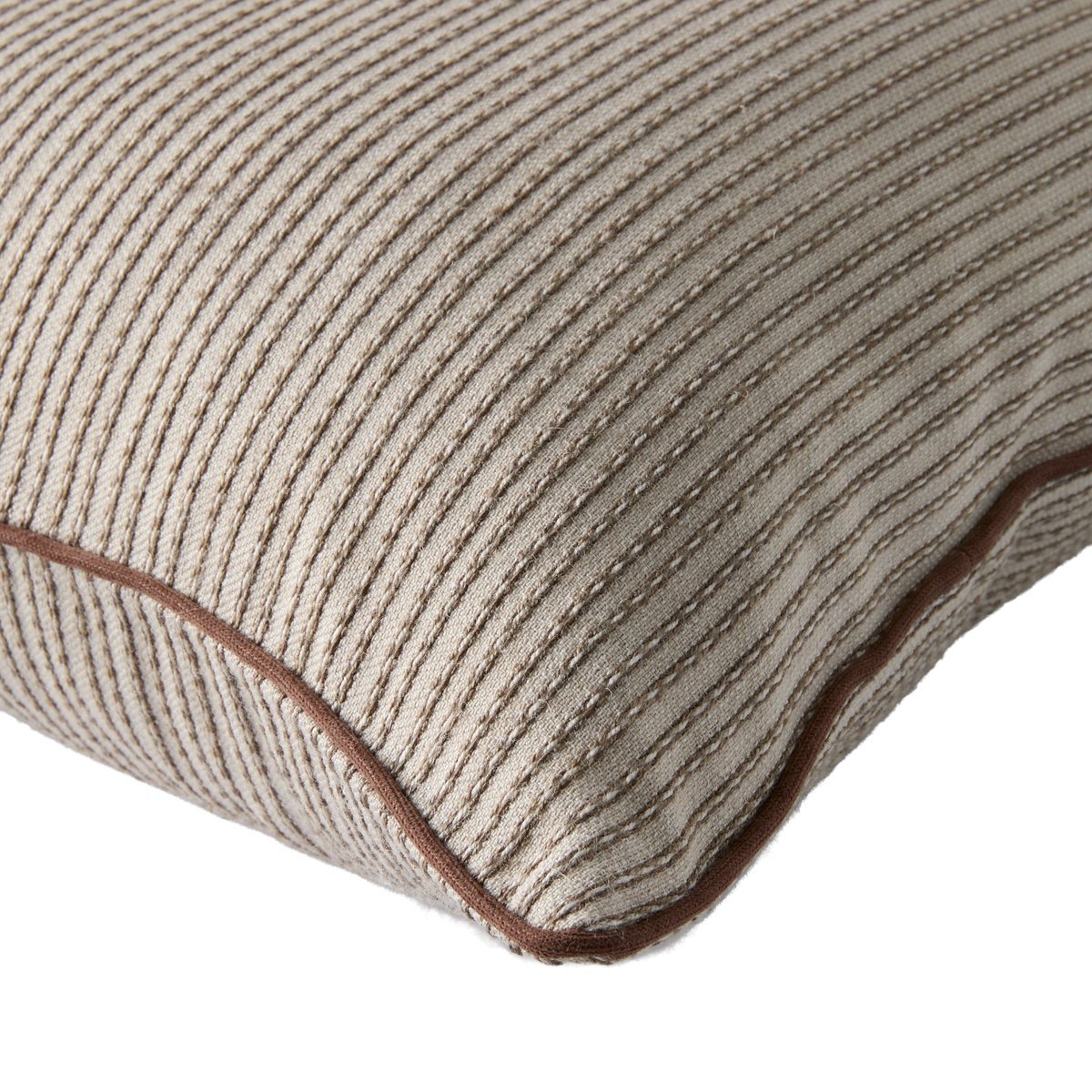 Nærbillede af beige pude med rillet struktur og brun piping.