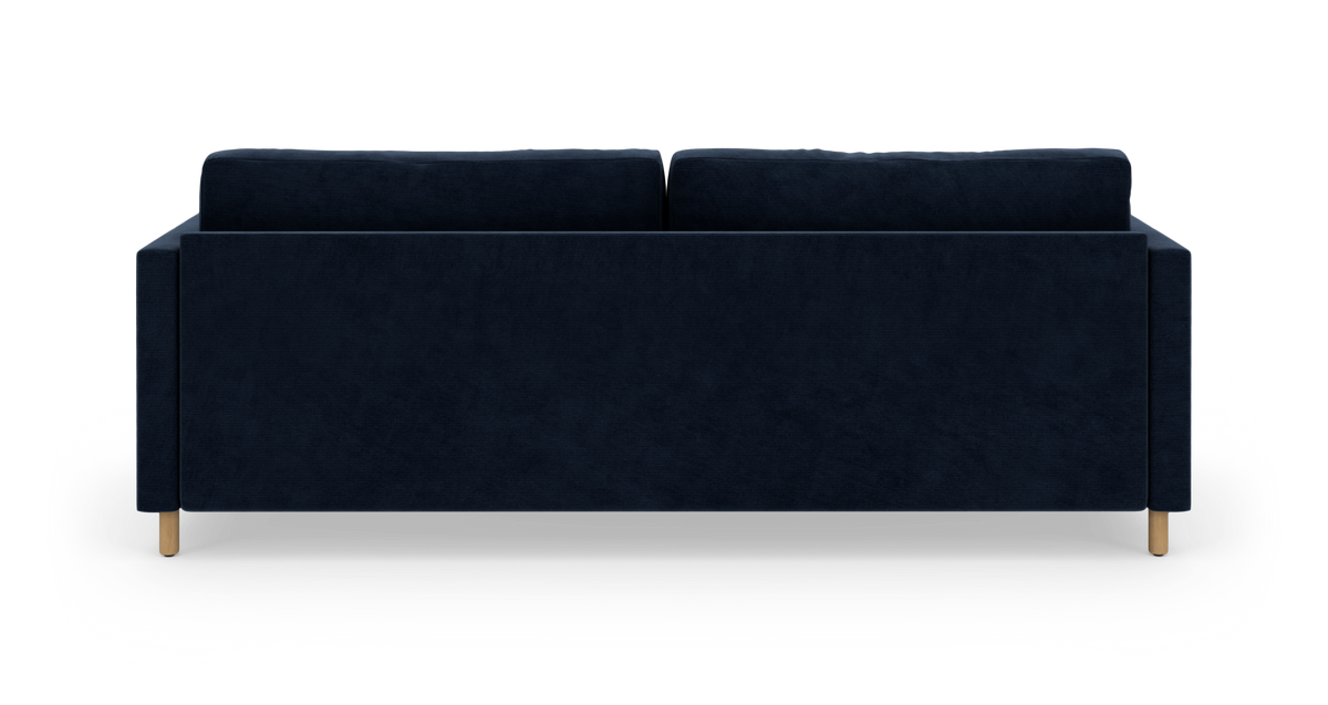 Mørkeblå sofa set bagfra på hvid studiobaggrund med lyse træben.