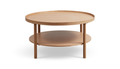 Rundt sofabord i lys eg med to hylder og forhøjet kant, minimalistisk design.