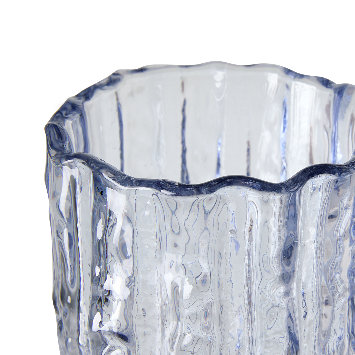 Nærbillede af bølgeformet glasvase i blåligt, struktureret glas mod hvid baggrund.
