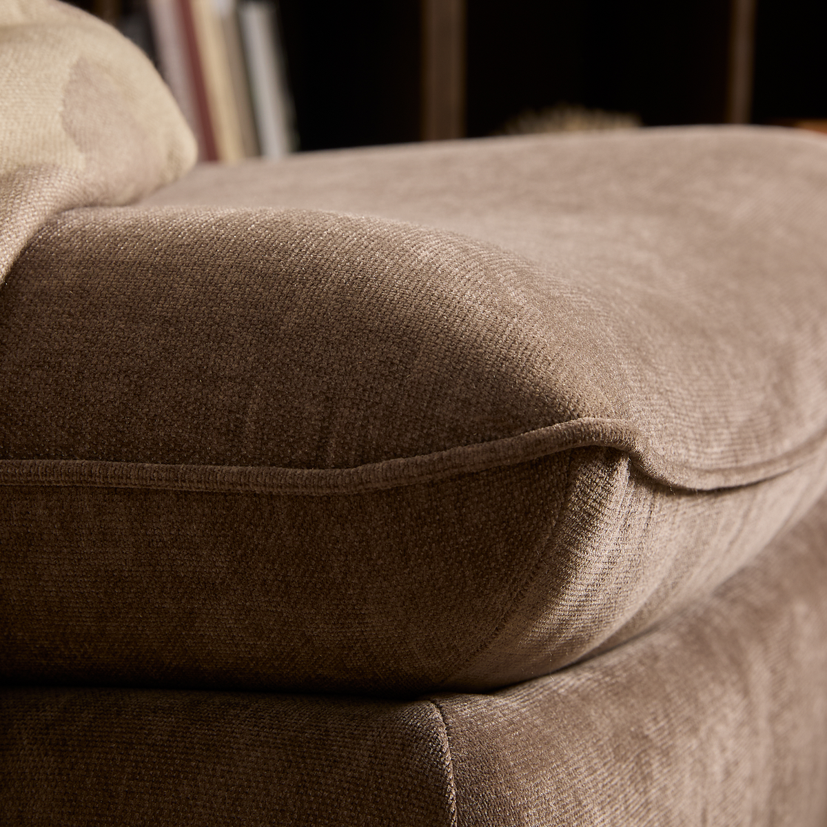 Nærbillede af brun/beige sofahynde i blødt stof med en plaid i hjørnet i en stue.