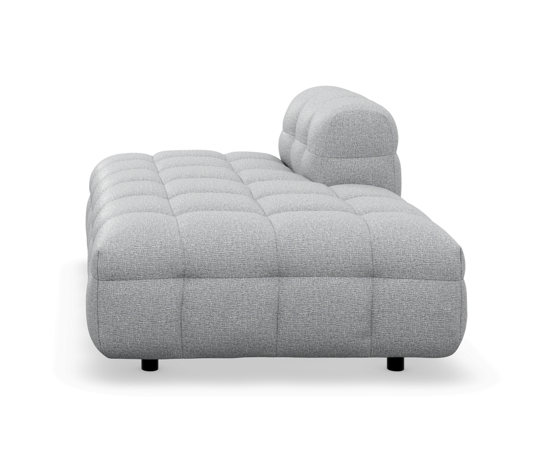 Grå tuftet modulsofa/chaise med lav profil, frilagt på hvid baggrund.