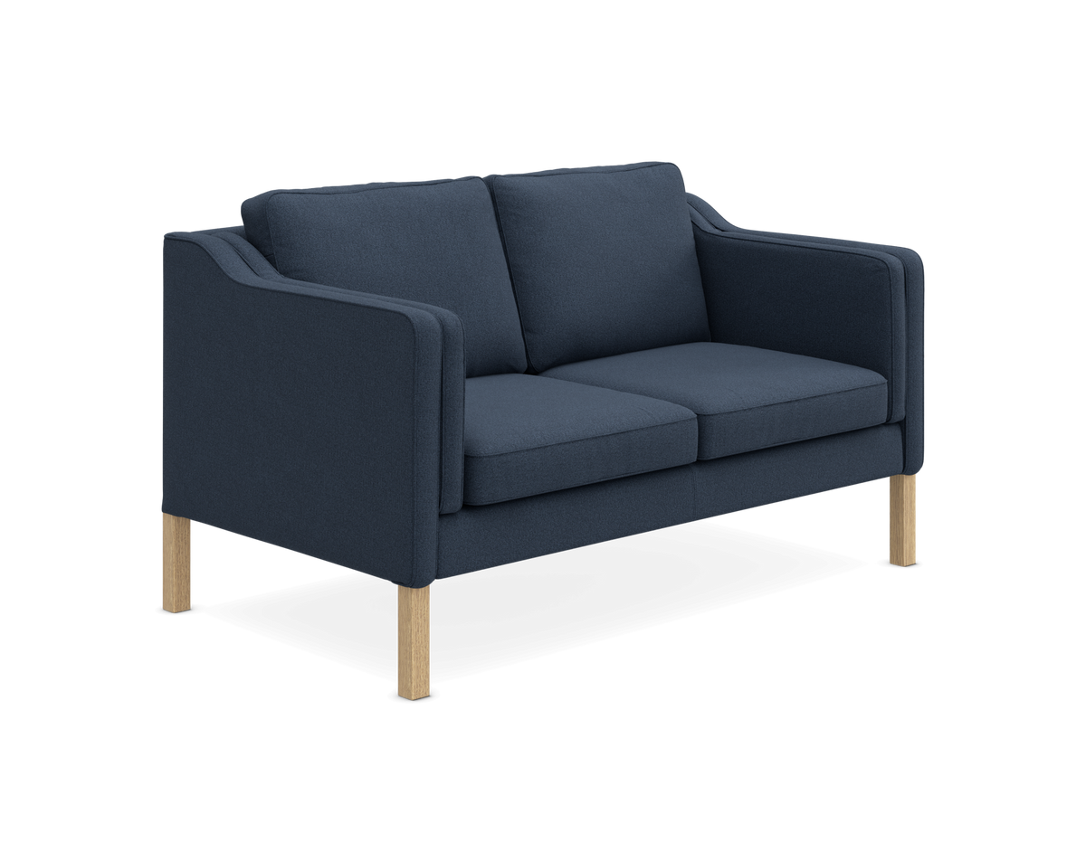 Mørkeblå 2-personers sofa med træben, frilagt på hvid baggrund.
