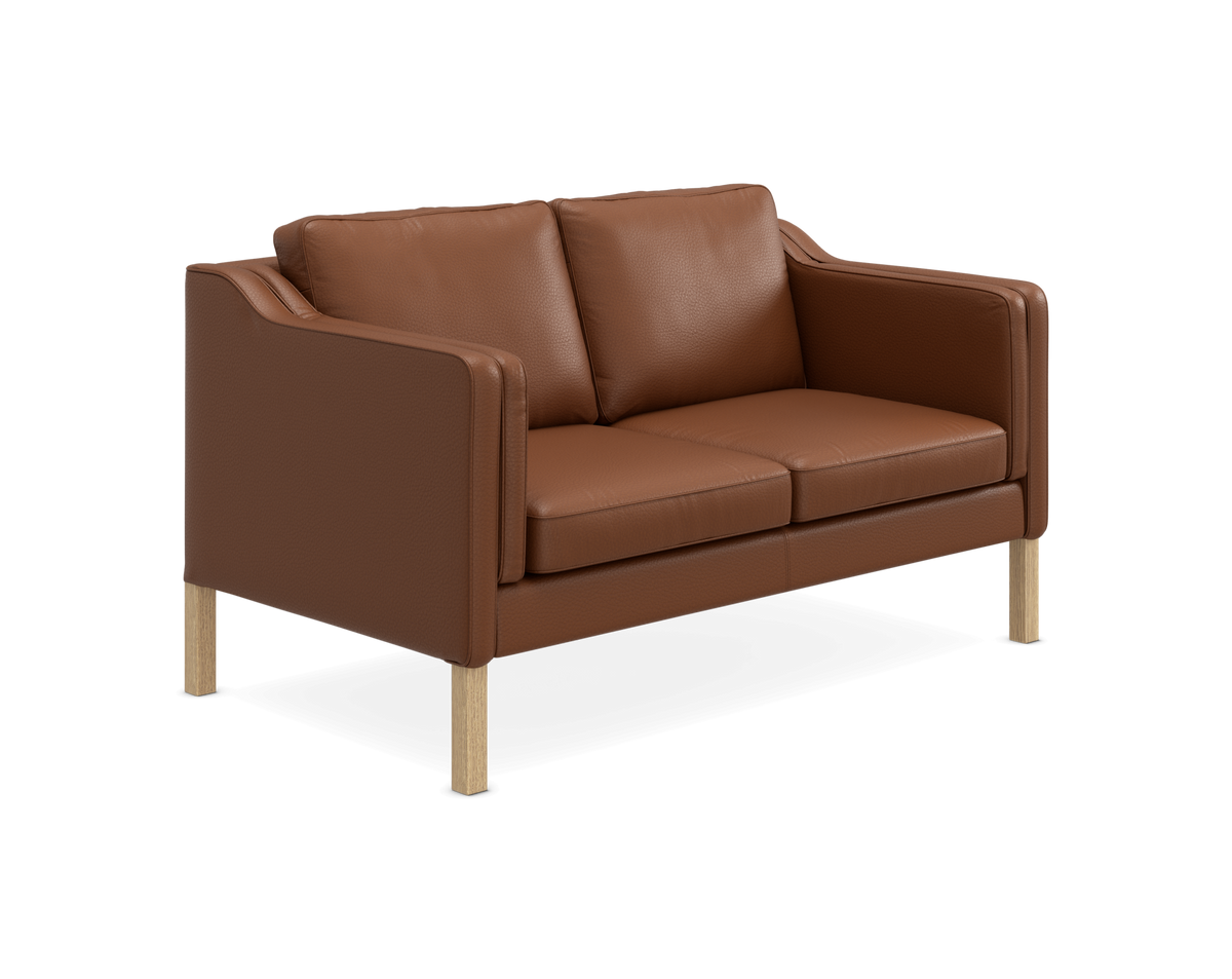 Tosædet sofa i brunt læder med lyse træben, fritlagt på hvid baggrund.