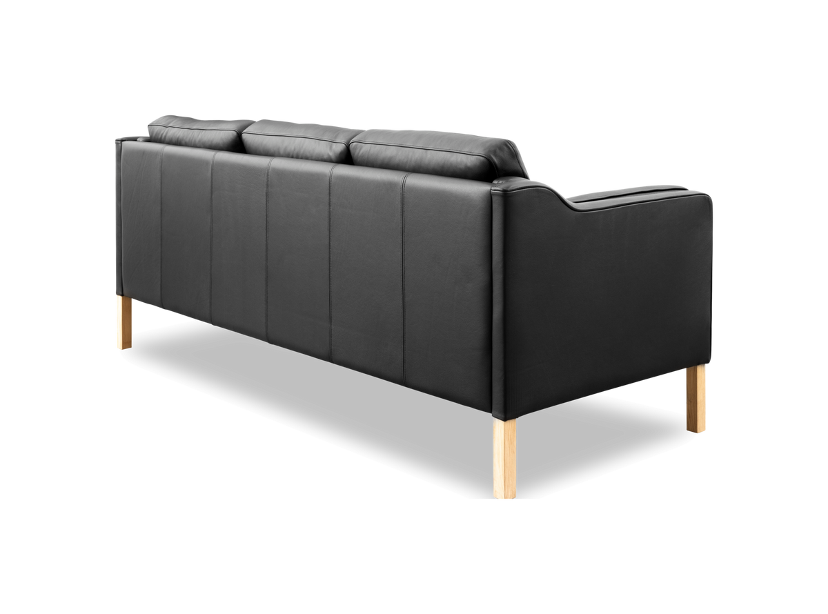 Sort lædersofa med lyse træben, set skråt bagfra, frilagt mod hvid baggrund.