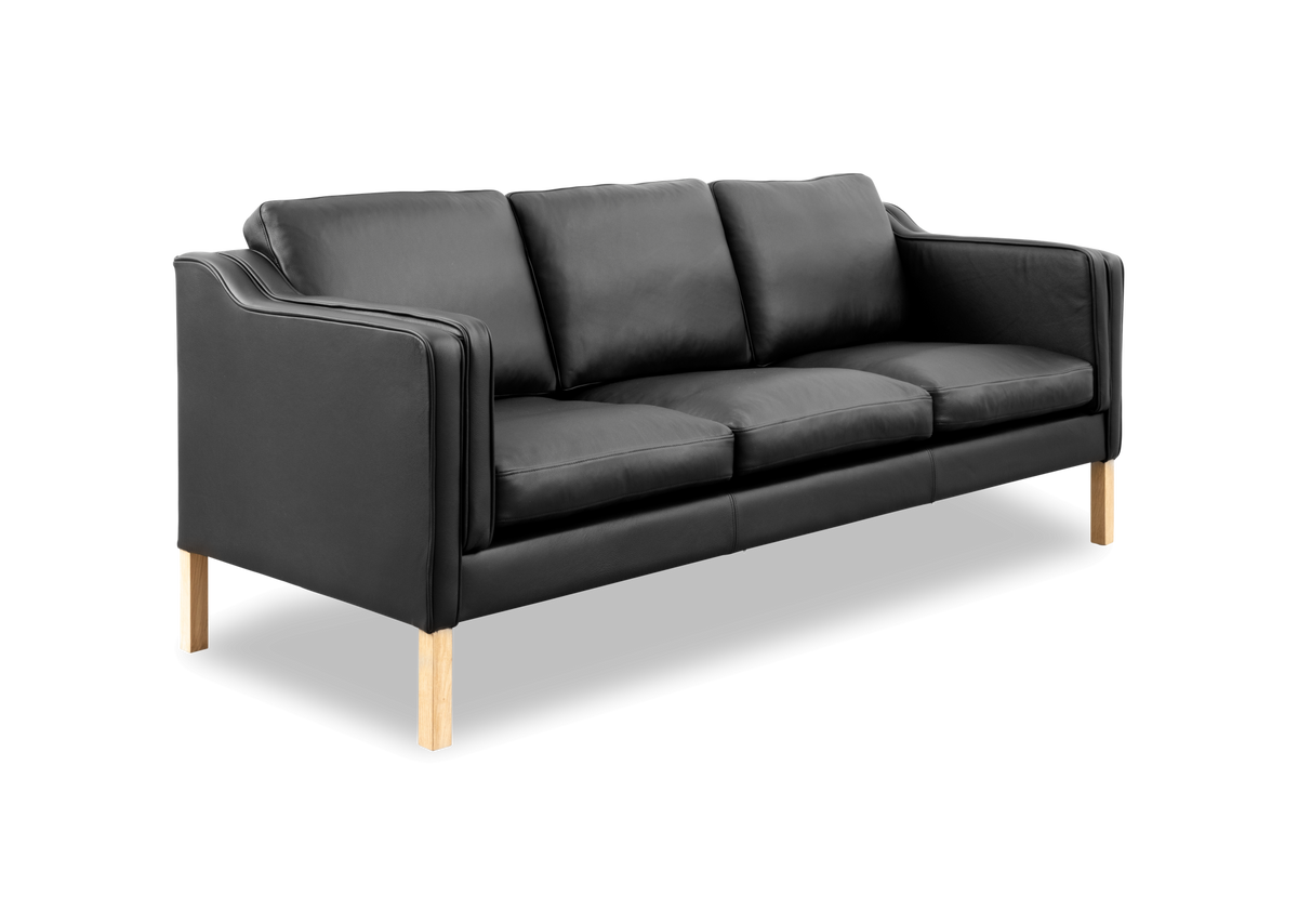 Sort lædersofa med tre sædehynder og lyse træben, frilagt.