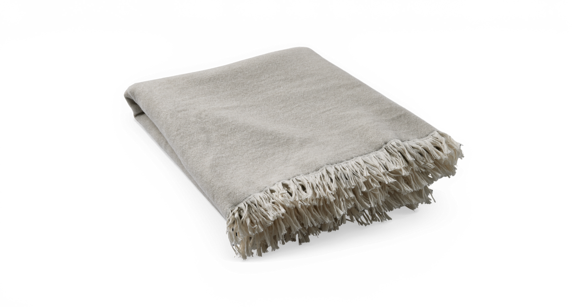 Beige plaid med frynser, sammenfoldet og frilagt mod neutral baggrund.