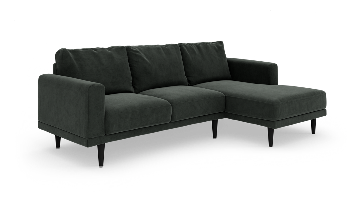 Mørkegrøn hjørnesofa med højre chaiselong og slanke sorte ben, fotograferet i studie.