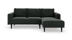 Mørkegrøn hjørnesofa med chaiselong til højre, på slanke sorte ben, fritlagt mod hvid baggrund.