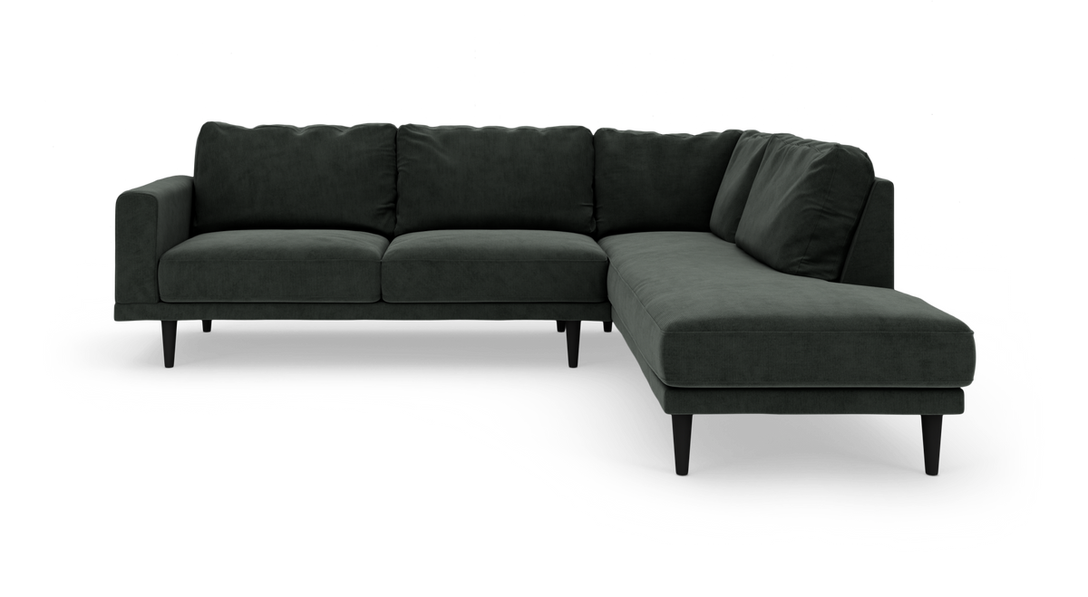 Mørkegrøn L‑sofa med chaiselong til højre og slanke sorte ben, fritlagt på hvid baggrund.