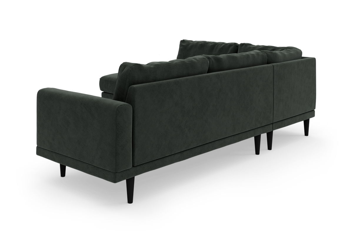 Mørkegrøn modulsofa set bagfra i studie med sorte ben.