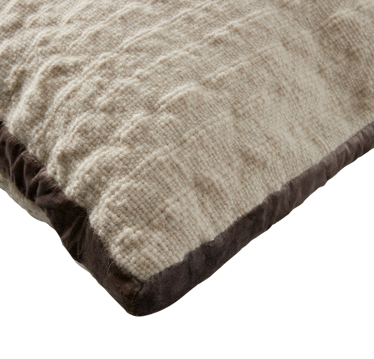 Beige strikket pude med mørkebrun velourkant, close-up.