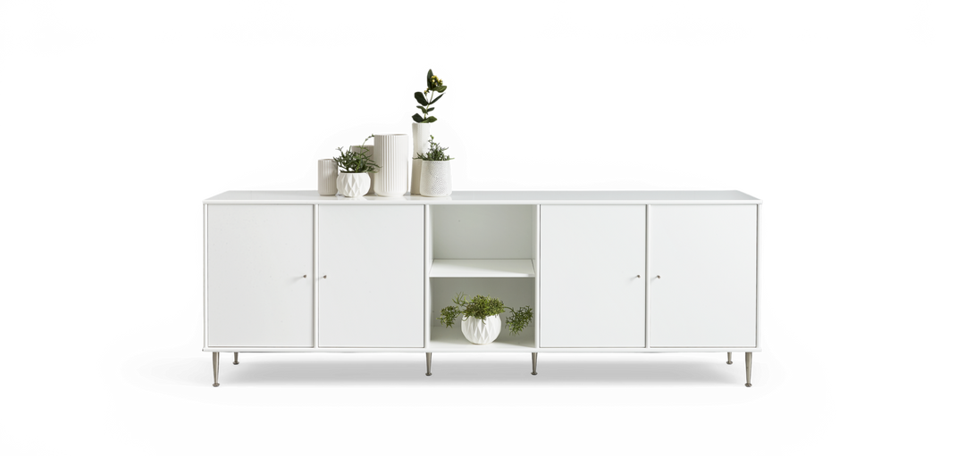 Hvid skænk med fire låger og åben hylde, stylet med hvide keramikvaser og grønne planter.