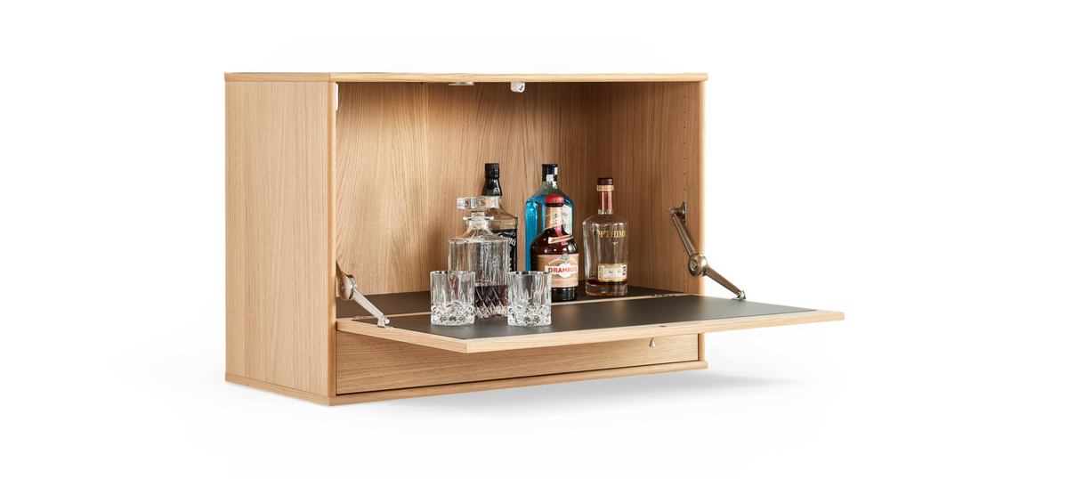 Vægmonteret barskab i eg med nedklappelig låge som bliver serveringsflade, med krystalkaraffel, glas og spiritusflasker som bl.a. Drambuie.