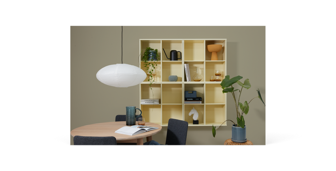 Minimalistisk sort mockup med en stor stående ram, ovalt spejl, bord og en potteplante.