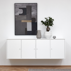 Vægmonteret hvid skænk med abstrakt gråt kunstværk ovenover, grå vase, lille dekoration og grøn plante i hvid krukke i en lys, minimalistisk indretning.