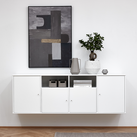 Hvid væghængt skænk i minimalistisk stil; på toppen står en grå kande, en bonsai i hvid potte og en lille dekoration, og over den hænger et abstrakt kunstværk. I hylden ligger bøgerne ”Dior” og ”Kinfolk” samt to grå opbevaringskasser.