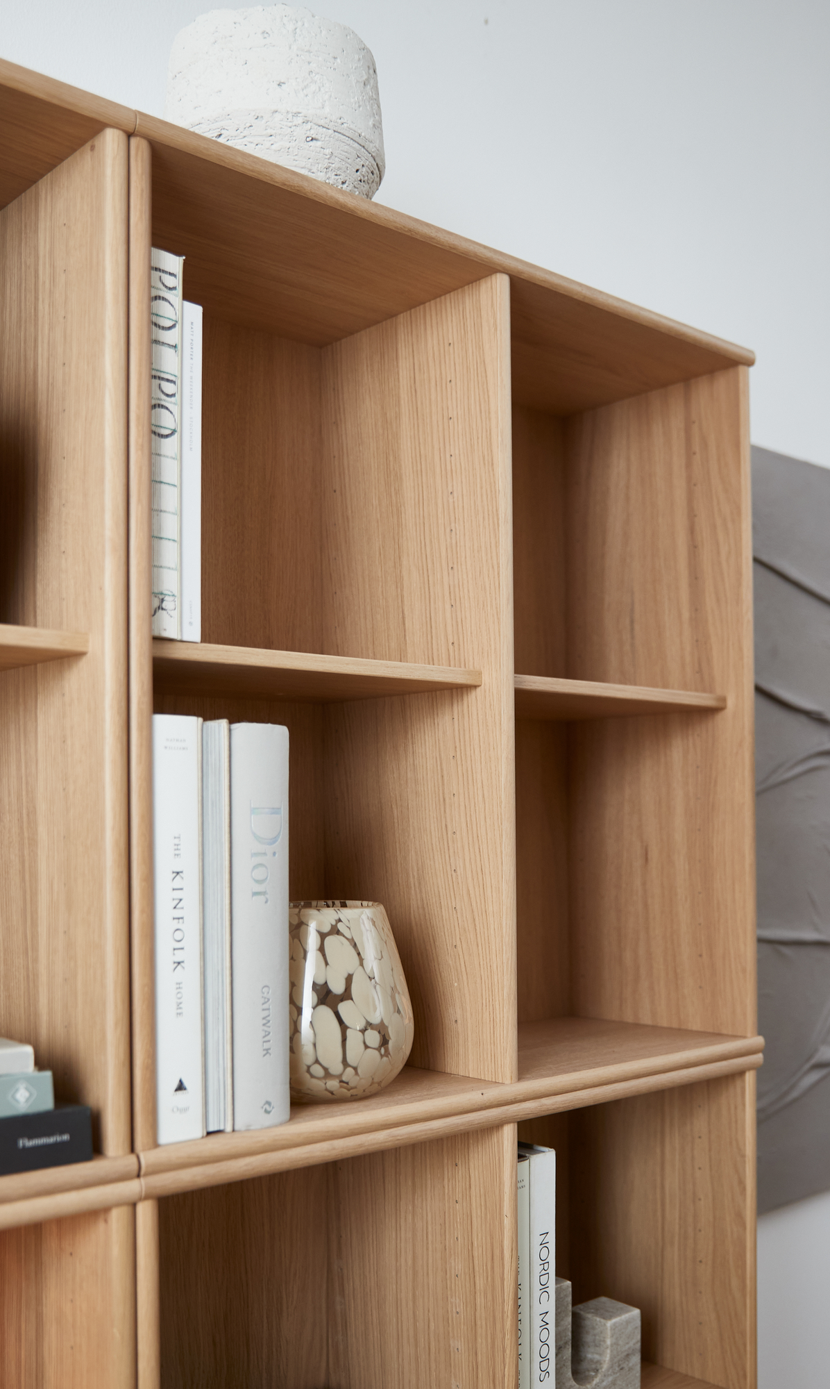 Træreol med bøgerne ”Dior”, ”The Kinfolk Home”, ”Nordic Moods” og en beige mønstret vase.