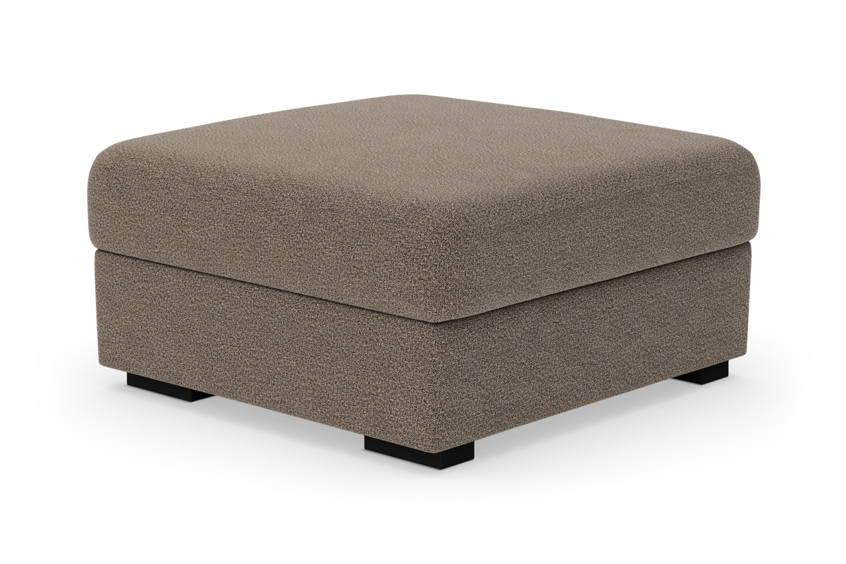 Firkantet puf/ottoman i beige stof med lave sorte ben, frilagt på hvid baggrund.