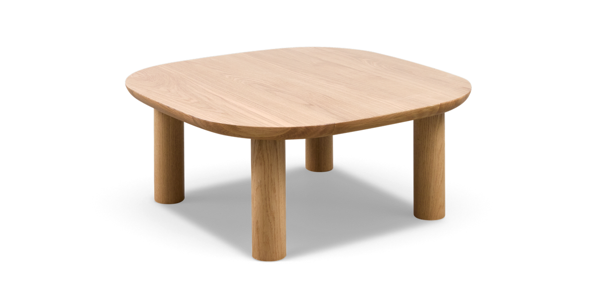 Isoleret produktfoto af lavt sofabord i lys eg med afrundede hjørner og fire cylindriske ben.