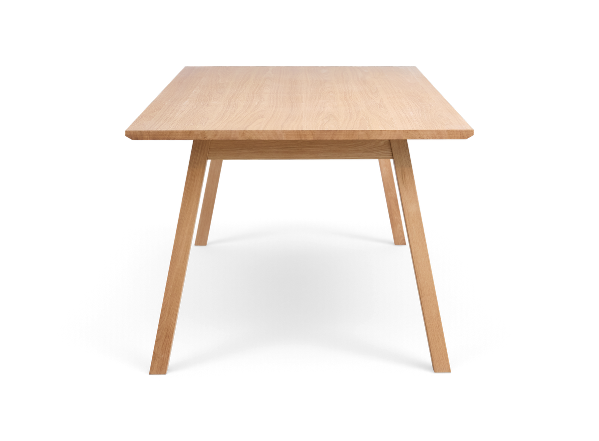 Rektangulært spisebord i lys eg med skrå ben, frontview, fritlagt baggrund.