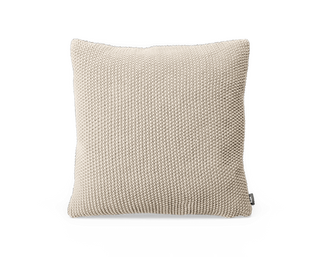 Beige strikket pyntepude med grov tekstur i kvadratisk form.